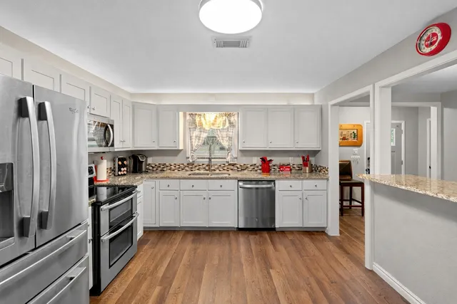 a kitchen with a sink wooden floor and stainless steel appliances