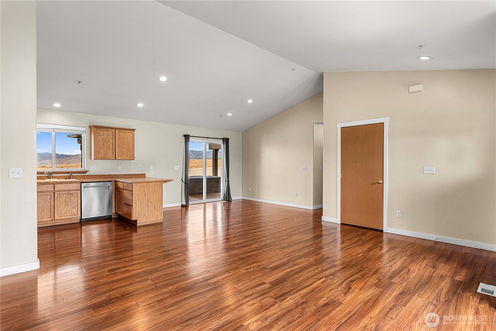 1308 Tractor Loop East Wenatchee, WA 98802 - Photo 9 of 35 a view of an empty room with wooden floor and a kitchen