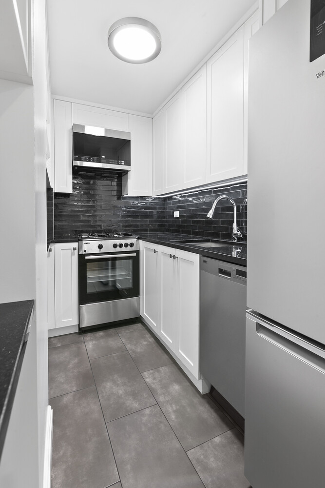 211 East 53rd Street, Unit 3M Manhattan, NY 10022 - Photo 4 of 11 a kitchen with stainless steel appliances granite countertop a stove top oven and sink