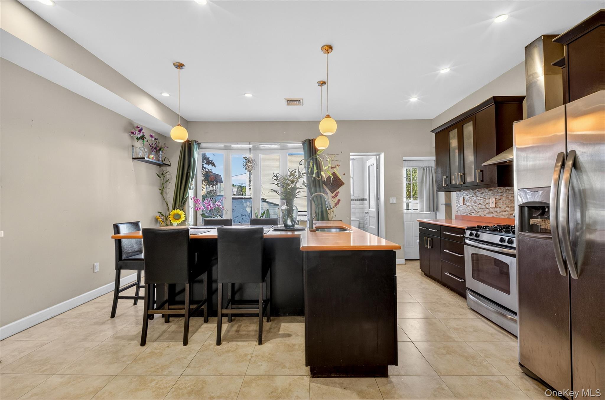 88-42 87th Street Queens, NY 11421 - Photo 9 of 33 a kitchen with stainless steel appliances granite countertop a table chairs and a refrigerator