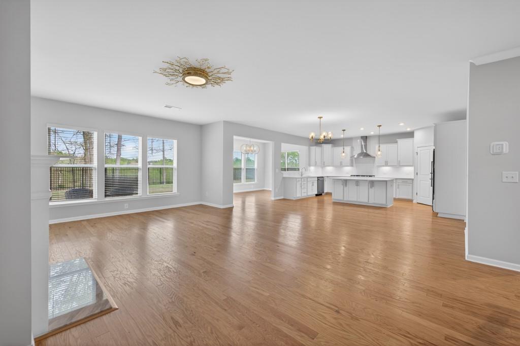 7277 Maple Brook Lane Flowery Branch, GA 30542 - Photo 18 of 57 a view of empty room with wooden floor and kitchen view