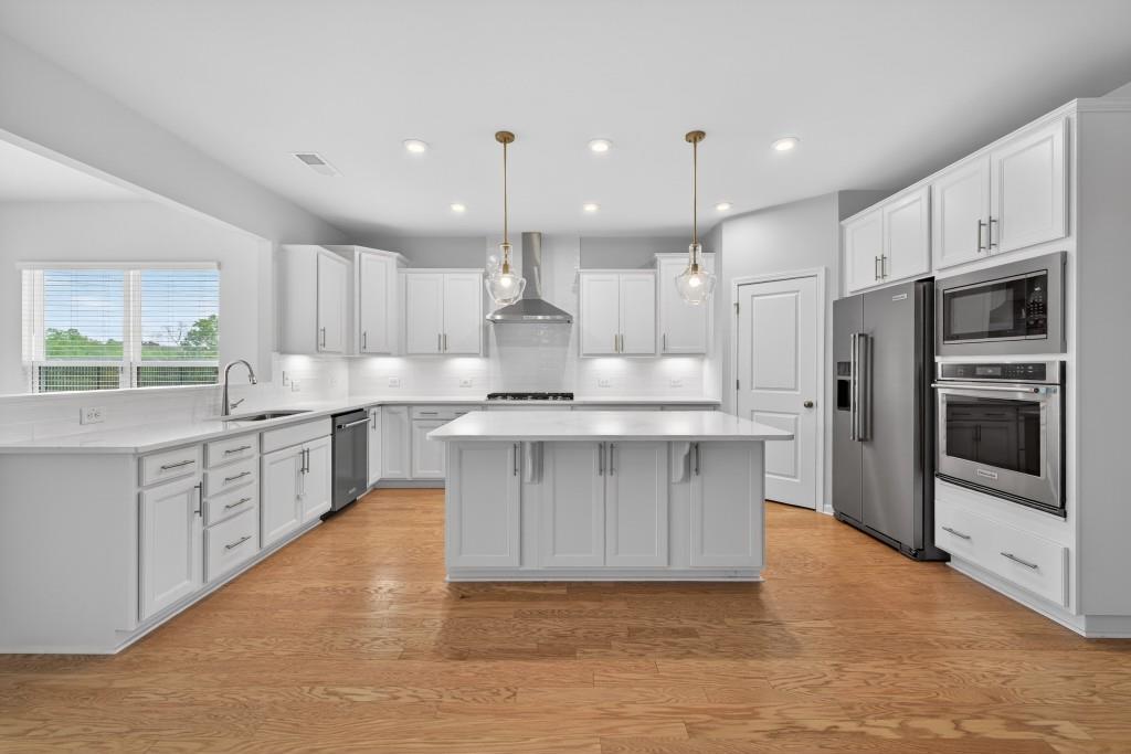 7277 Maple Brook Lane Flowery Branch, GA 30542 - Photo 21 of 57 a kitchen with kitchen island granite countertop a stove a sink and a refrigerator