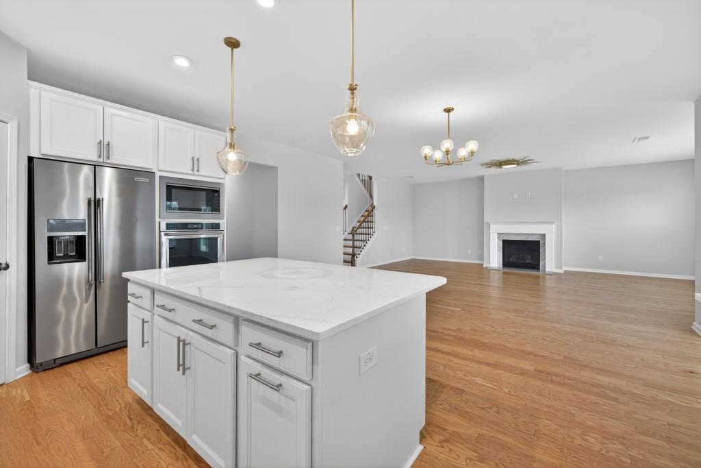 7277 Maple Brook Lane Flowery Branch, GA 30542 - Photo 23 of 57 a kitchen with kitchen island a sink stainless steel appliances and wooden floor