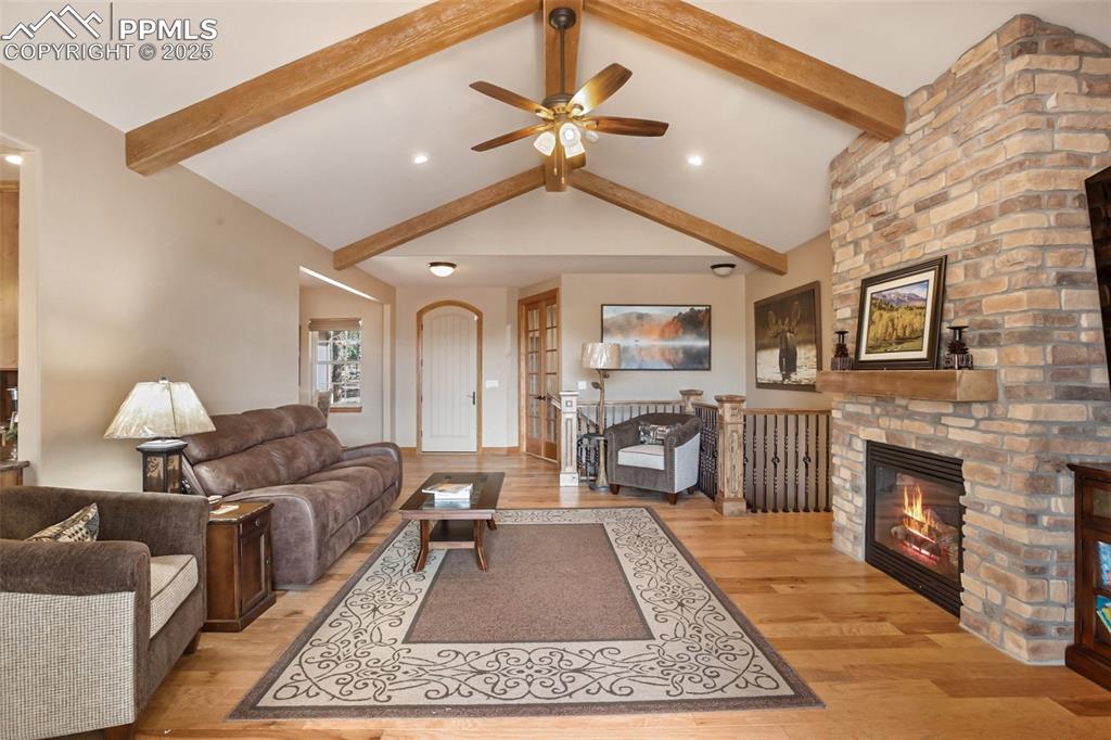 5070 Vessey Road Colorado Springs, CO 80908 - Photo 11 of 49 Living room featuring beam ceiling, ceiling fan, a fireplace, and light wood finished floors