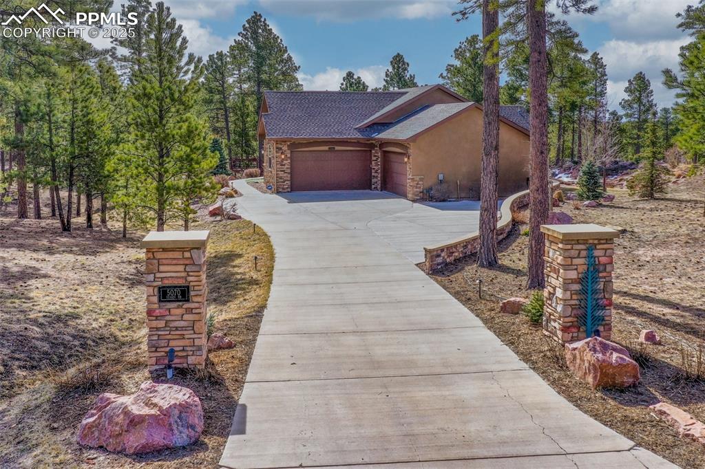 5070 Vessey Road Colorado Springs, CO 80908 - Photo 2 of 43 View of front of house featuring stucco siding, stone siding, concrete driveway, an attached garage, and a shingled roof