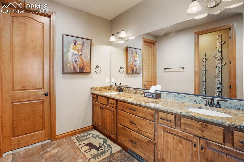 5070 Vessey Road Colorado Springs, CO 80908 - Photo 24 of 49 Bathroom featuring double vanity, baseboards, and a sink