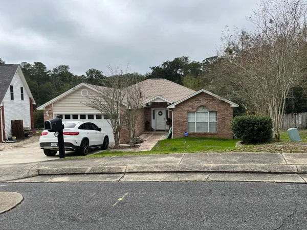 a white house with a large parking space and a car parked in front of it