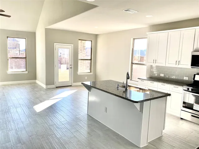 a kitchen with stainless steel appliances granite countertop a sink a stove and wooden floor