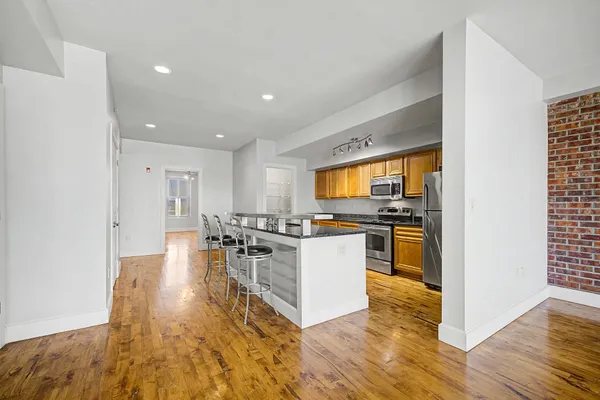 a kitchen with stainless steel appliances granite countertop a stove top oven a sink a dining table and chairs with wooden floor