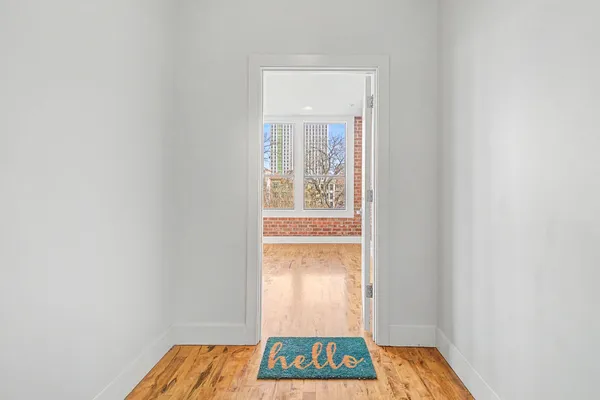 a view of an empty room with window and wooden floor