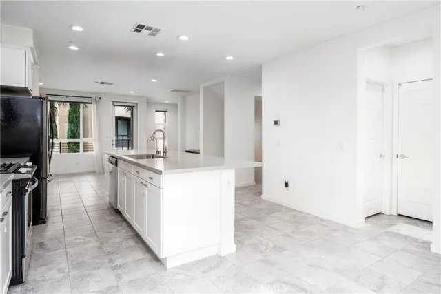 a large kitchen with stainless steel appliances a large counter top a stove and a refrigerator