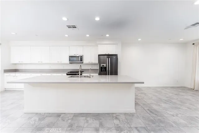 a large white kitchen with a sink a counter top space and stainless steel appliances