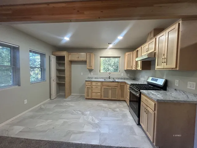 a large kitchen with stainless steel appliances granite countertop a stove a sink dishwasher and a refrigerator