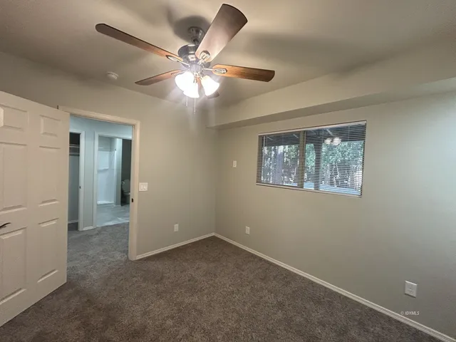 an empty room with windows and fan
