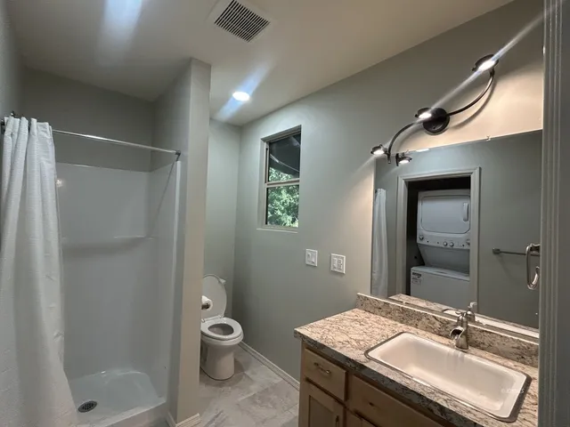 a bathroom with a granite countertop sink a toilet a shower and a mirror