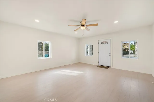 an empty room with windows and ceiling fan