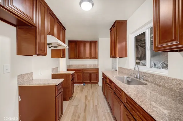 a kitchen with stainless steel appliances granite countertop wooden cabinets a sink and dishwasher a stove top oven with wooden floor