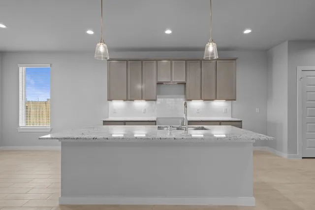 a kitchen with kitchen island granite countertop a stove and a refrigerator with wooden floors
