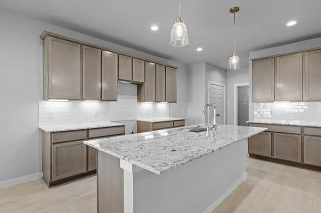 a kitchen with kitchen island granite countertop a sink a counter space appliances and cabinets