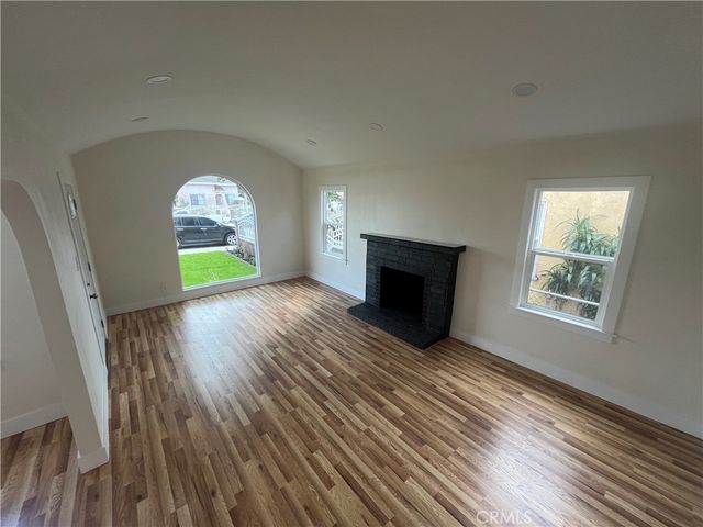an empty room with a fireplace and wooden floor
