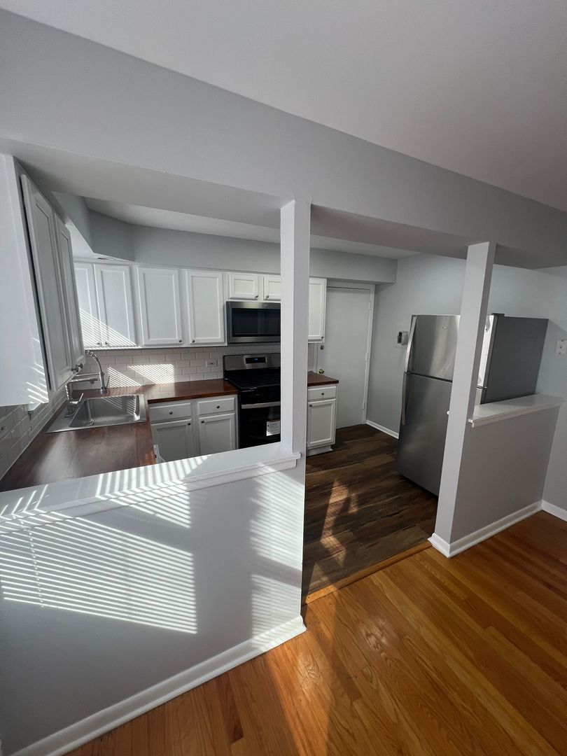 2348 West 111th Street, Unit 2 Chicago, IL 60643 - Photo 12 of 23 a kitchen with stainless steel appliances wooden floors wooden cabinets a refrigerator and a stove