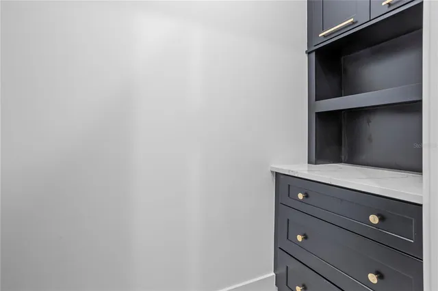 a large white kitchen with a large counter top stainless steel appliances and cabinets