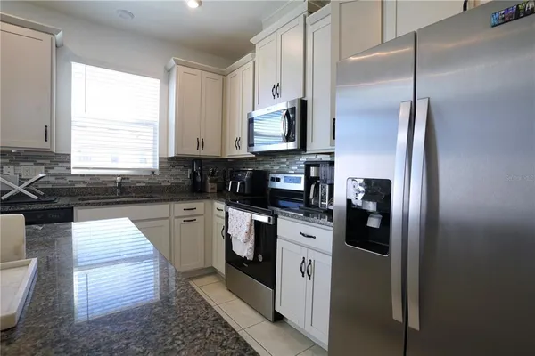 a kitchen with granite countertop a refrigerator stove top oven and sink