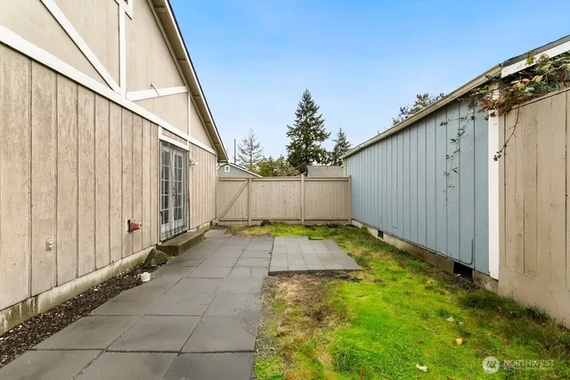 a view of a house next to a big yard with plants and large trees