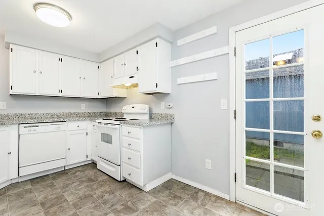 a kitchen with granite countertop white cabinets and white appliances