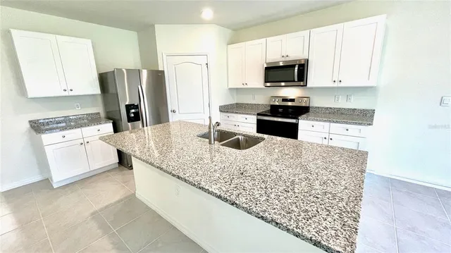 a kitchen with stainless steel appliances granite countertop a stove refrigerator and a microwave