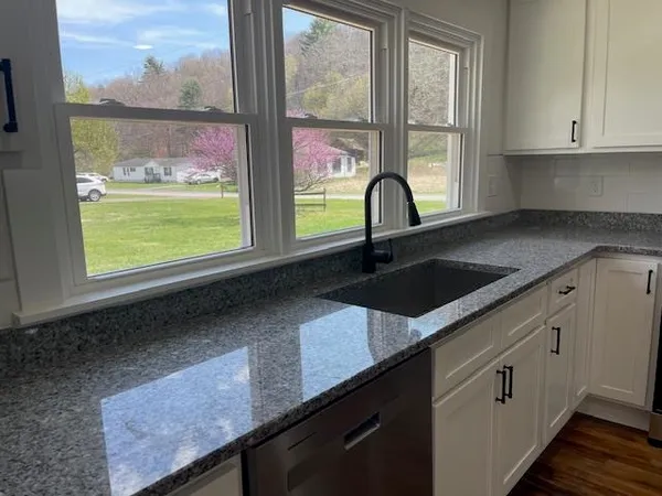 a kitchen with granite countertop a window a sink and cabinets