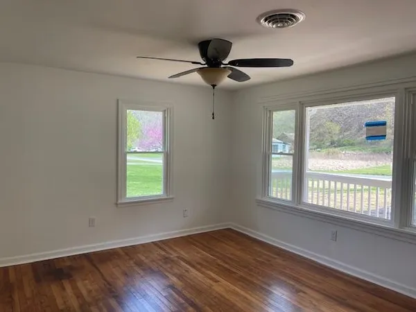 a view of an empty room with wooden floor and a window