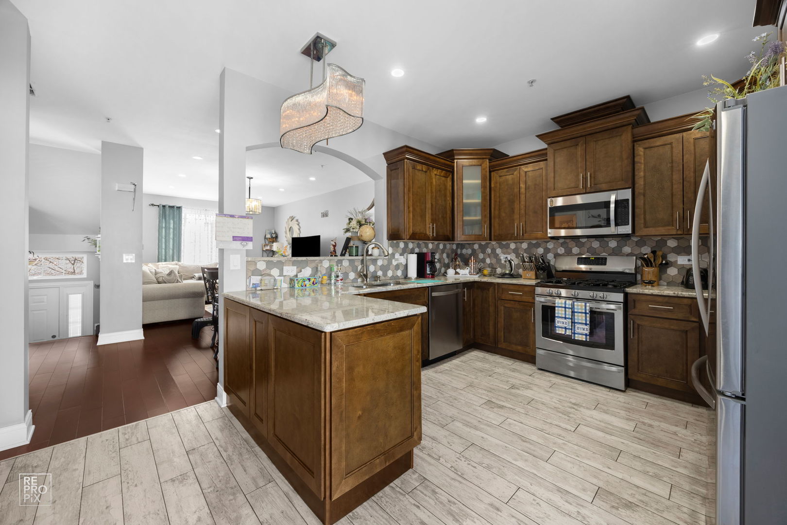 7504 Claridge Drive, Unit E Bridgeview, IL 60455 - Photo 7 of 25 a kitchen with stainless steel appliances kitchen island granite countertop a large stove a sink dishwasher and a refrigerator with wooden floor