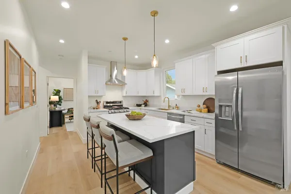 a kitchen with stainless steel appliances granite countertop a refrigerator a sink dishwasher a stove and white cabinets with wooden floor