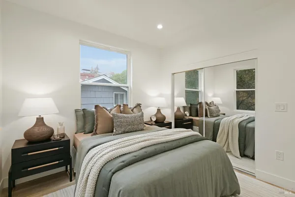 a bedroom with two beds and a large mirror next to a window