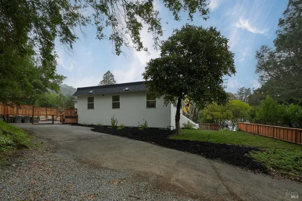 a view of a house with a yard and large tree