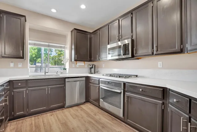 a kitchen with stainless steel appliances granite countertop a stove a sink and a microwave