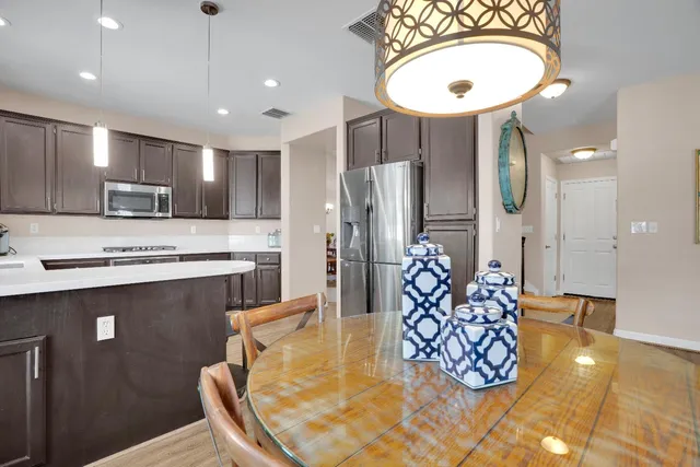 a kitchen with stainless steel appliances granite countertop a sink a stove a oven a dining table and chairs