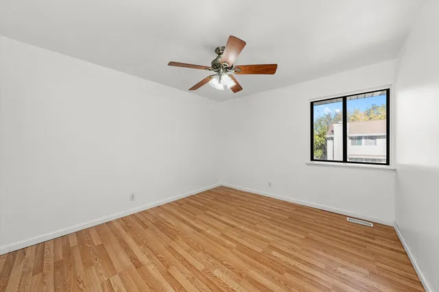 a view of a big room with wooden floor and a ceiling fan