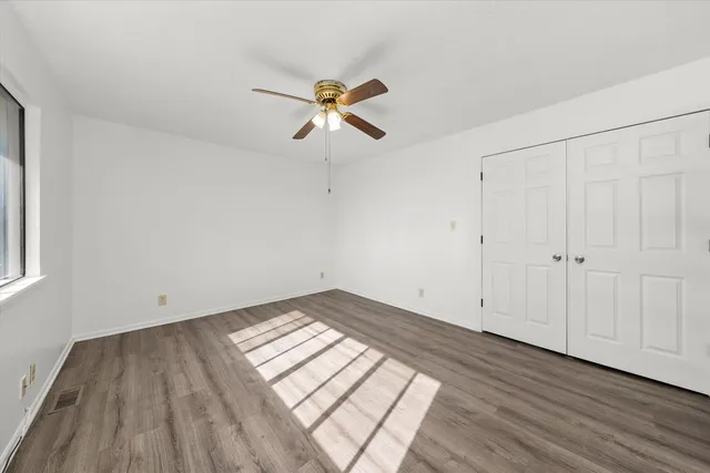 a view of empty room with wooden floor and fan