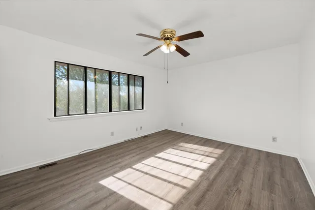 a view of empty room with wooden floor and fan
