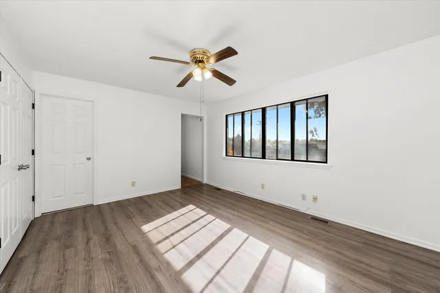 a view of empty room with wooden floor and fan