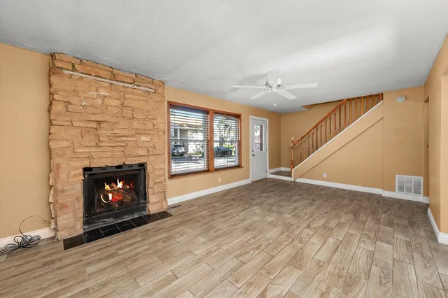 a view of an empty room with wooden floor fireplace and a window