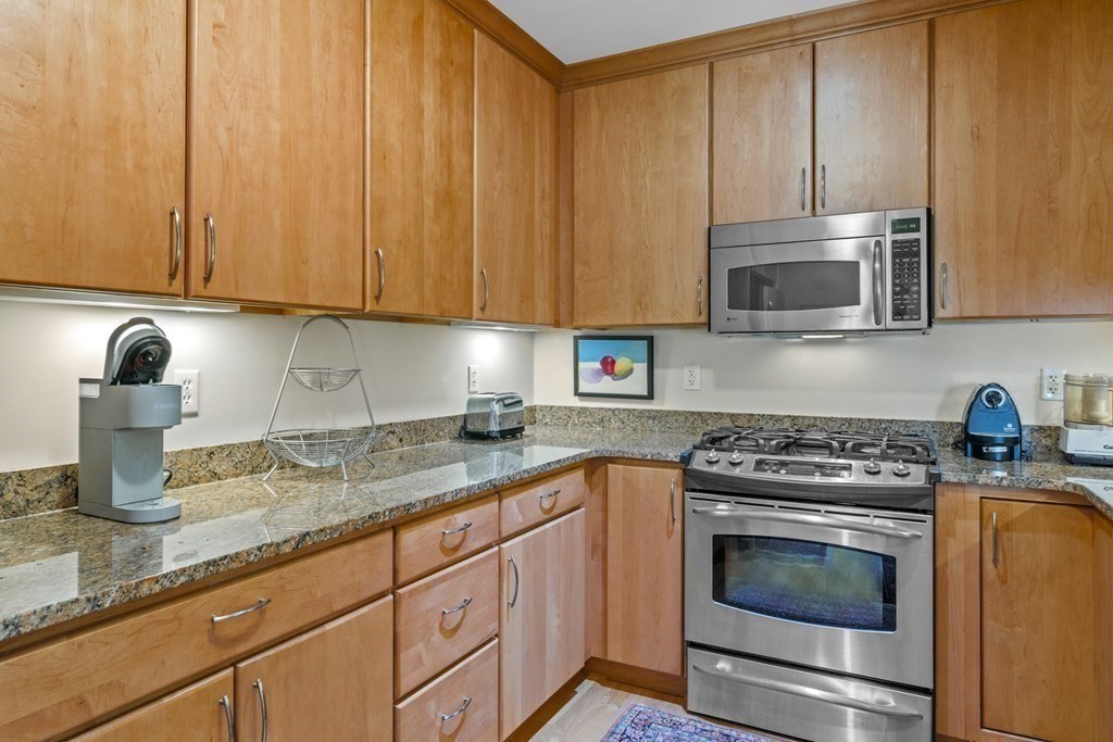 36 Intrepid Circle, Unit 303 Marblehead, MA 01945 - Photo 7 of 22 a kitchen with granite countertop a stove top oven microwave and cabinets