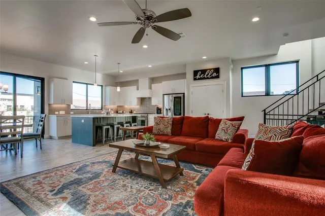 a living room with furniture kitchen view and a wooden floor