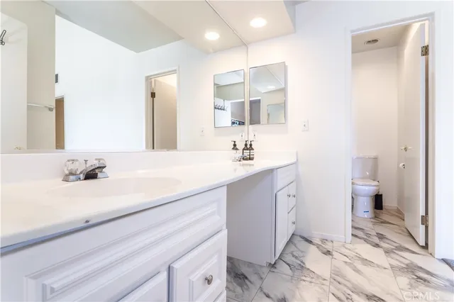 a spacious bathroom with a sink a toilet and a mirror