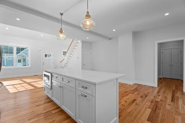 a view of a living room and kitchen view with wooden floor