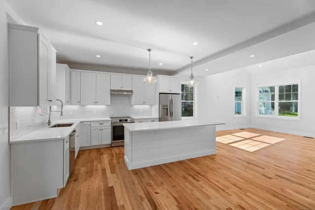 a kitchen with a sink dishwasher a stove and a refrigerator with wooden floor