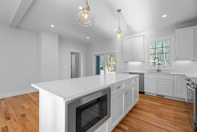 a kitchen with a sink dishwasher a stove and white cabinets with wooden floor