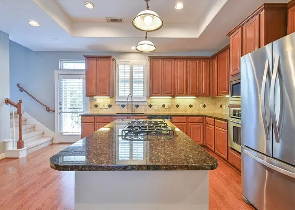 a kitchen with stainless steel appliances granite countertop a refrigerator a stove and a sink with wooden floor
